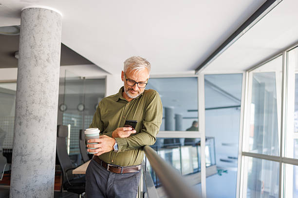 istock Mature businessman checking smartphone during coffee break in office 2241450726