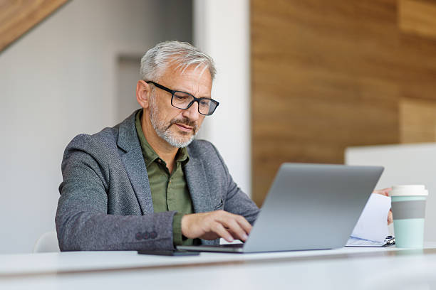 istock Mature businessman working on laptop in modern office 2241451032