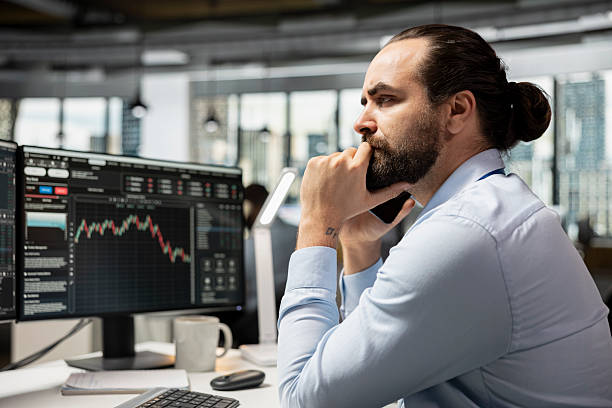 istock Investment consultant frowning while looking at candlestick charts 2241456959
