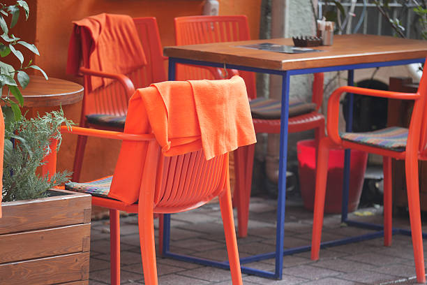 Vibrant orange chairs and table set up for dining in a cozy outdoor space.