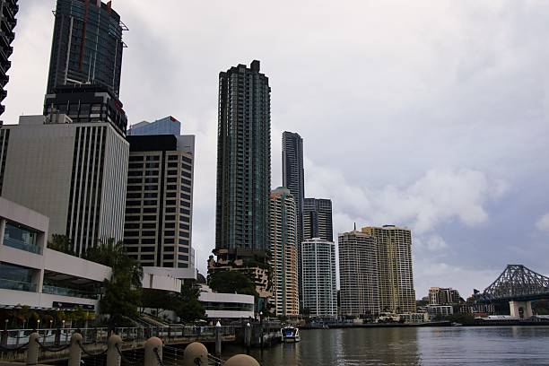 Towering high-rise buildings and a busy waterfront scene in the heart of a modern city under a cloudy sky.
