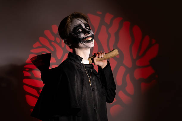 Young vampire boy holding a bat, ready for trick-or-treating on Halloween night.