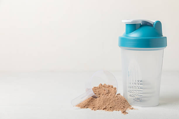 istock Protein shake with protein powder on a colored background. The powder is mixed with water or milk. A dietary supplement for a balanced diet. Whey protein. Fitness and gym diet nutrition. 2241460893
