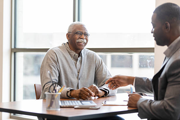 istock Smiling senior man consults with a younger professional in an office setting. 2241463121