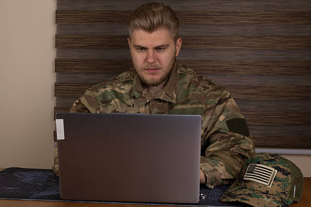 istock Man in military uniform using laptop in a bustling airport terminal 2241464850