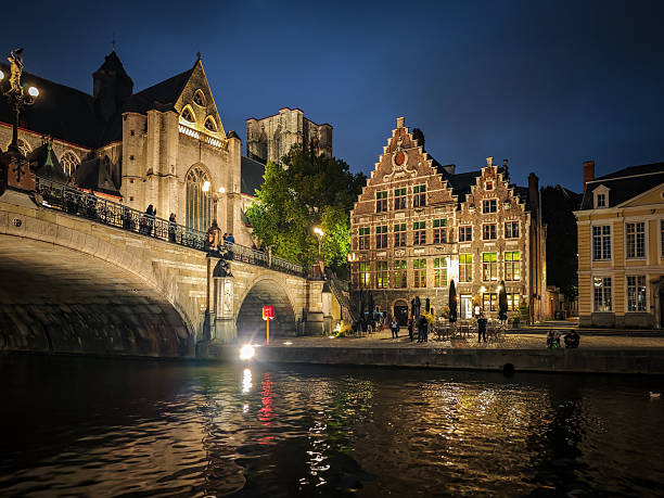 Ghent, Belgium. 12 October 2025. Saint Michael's Bridge in Ghent at night with people in the city.