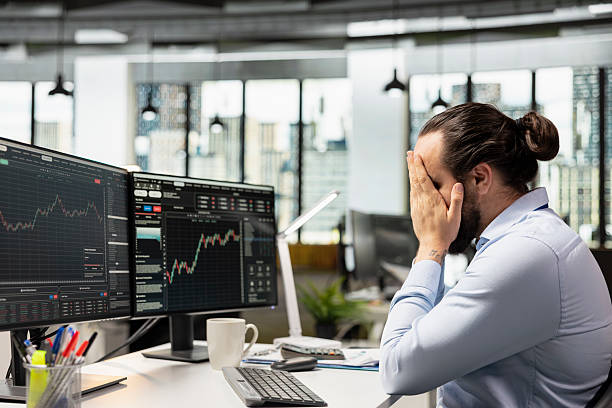 istock Trader reacting negatively to poor portfolio performance, covering face 2241466309
