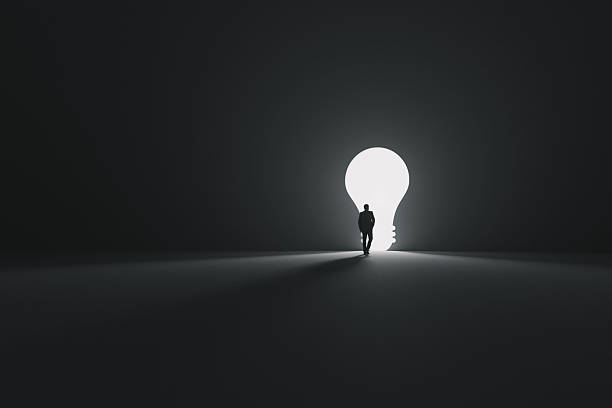 istock Man walking toward a giant glowing light bulb door. Innovation, creativity, and new ideas. Concept of inspiration, success, leadership, and thinking outside the box in a dark space. Career, creative 2241469948