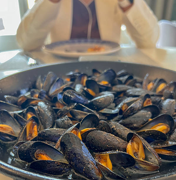 Steamed mussels ready to eat, with my wife in the background ready to enjoy them