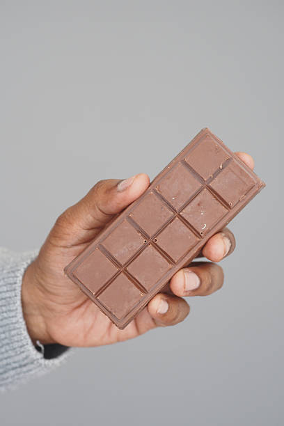 istock Chocolate bar held in hand against a neutral background 2241470911