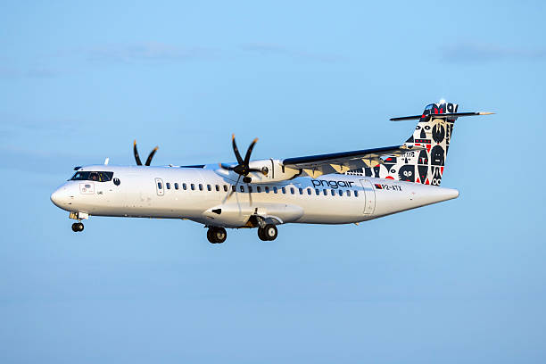 A white passenger airplane is parked at Santorini Airport, set against the backdrop of the picturesque tourist town of Santorini. The image captures the serene beauty of the coastal area, with the iconic white architecture and blue-domed buildings in the distance. This scene highlights the blend of modern travel and traditional charm, making it a perfect representation of the popular Greek island destination.