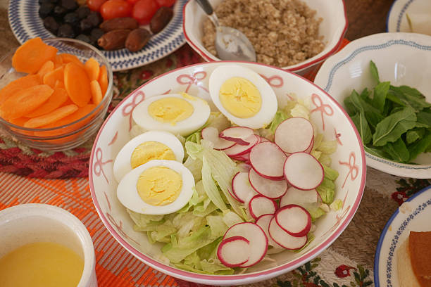 A vibrant salad features sliced eggs, radishes, lettuce, and carrots.