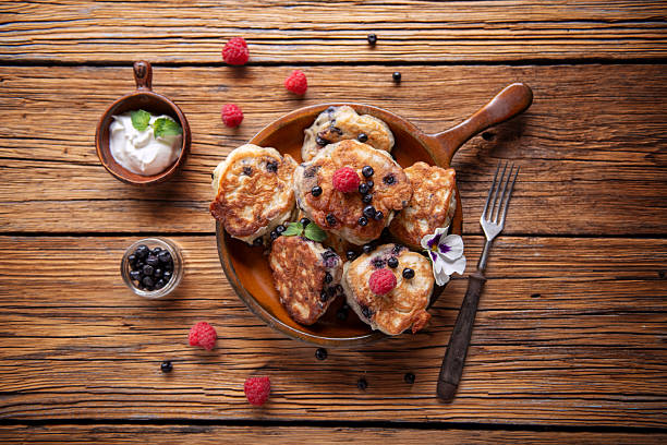 Rustic style pancakes served with berries on dark wooden board.