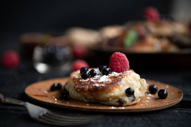 Plate of homemade pancakes served with fresh berries and cream.