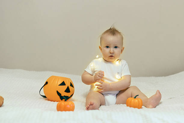 istock Baby Playing with Halloween Pumpkin on Bed 2241477100