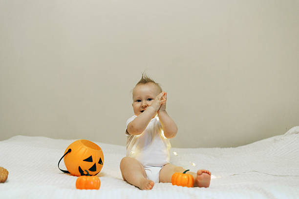 istock Baby Playing with Halloween Pumpkin on Bed 2241477128
