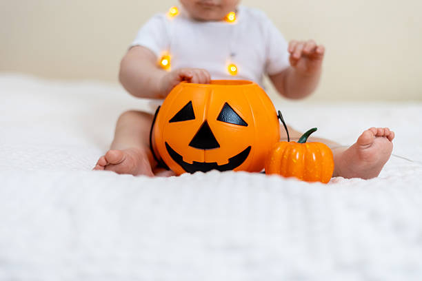 istock Baby Exploring Halloween Pumpkin on Cozy Blanket 2241477194