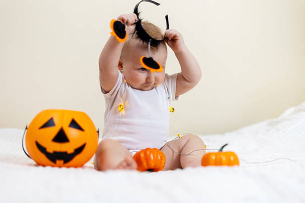 istock Baby Playing with Halloween Decorations on Bed 2241477395