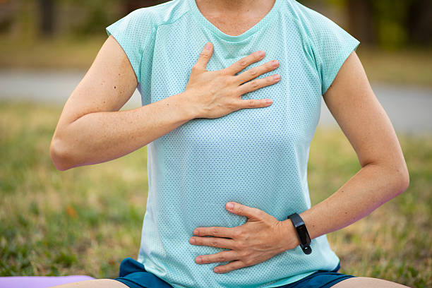 Woman practicing deep breathing exercise outdoor for mindfulness - stock image