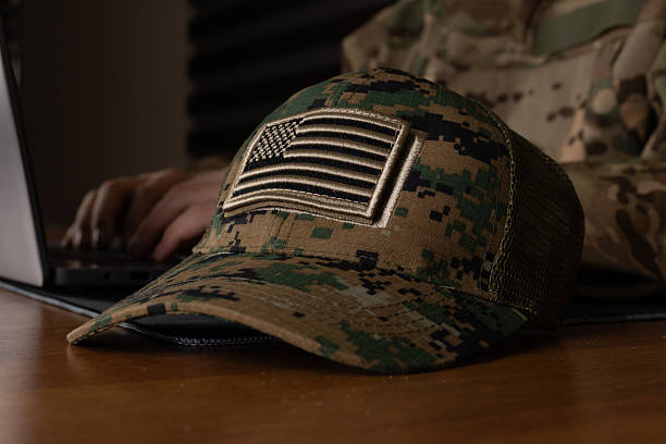 istock Soldier typing on a laptop in a military camp 2241479136