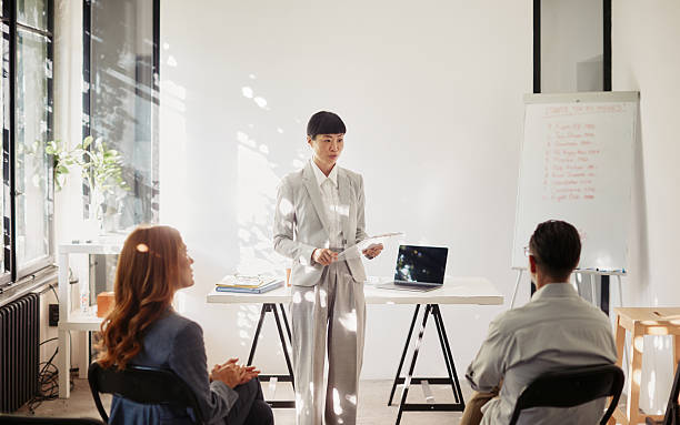 istock Confident Japanese-descent female presenter engaging a small audience in a training session 2241479690
