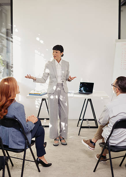 istock Confident Japanese-descent female presenter engaging a small audience in a training session 2241479781