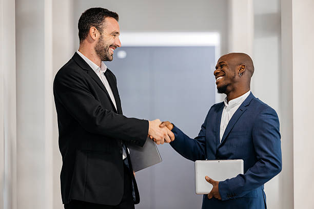 istock Two business people shaking hands in a modern office 2241480857