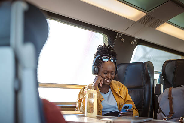 istock Traveler on a bright train ride using phone with headphones and backpack nearby 2241481968