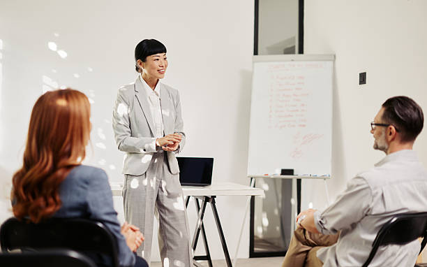 istock Confident Japanese-descent female presenter engaging a small audience in a training session 2241482017