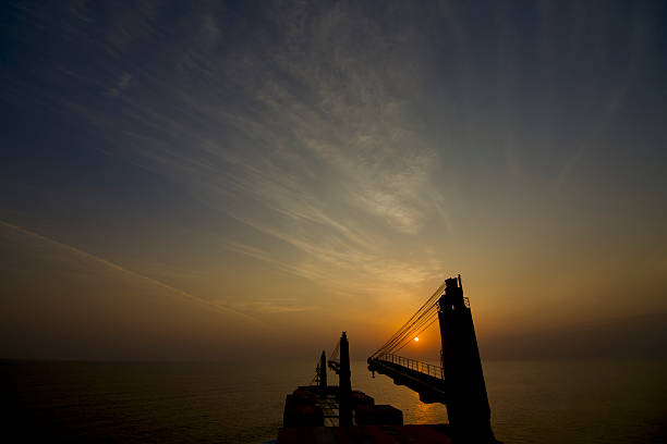Silhouettes of cargo ships on the horizon at sunset and sunrise
