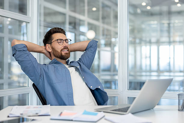 istock Relaxed businessman sitting at desk taking a break in modern workplace 2241482359