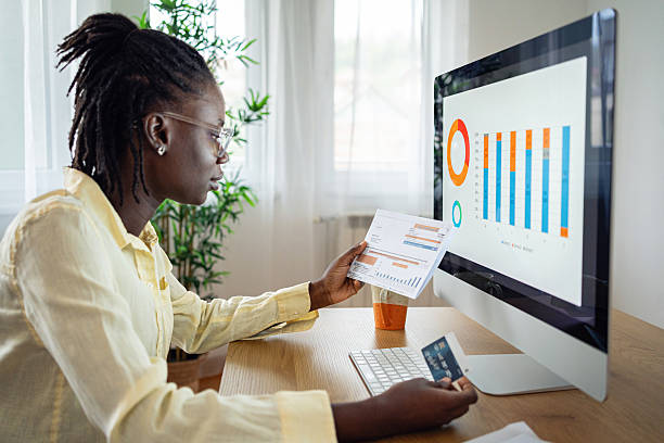 istock Young Black woman reviewing bills and credit card while analyzing financial charts on computer 2241486924