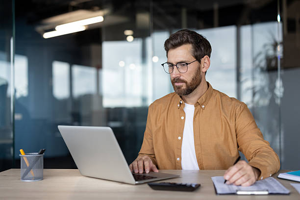 istock Businessman multitasking, working online, writing, and calculating 2241491473