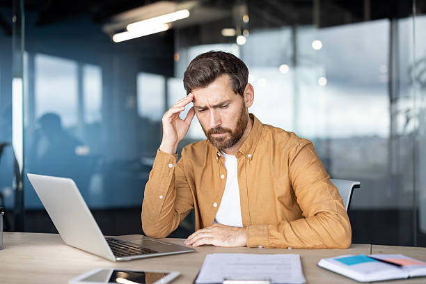 istock Businessman suffering headache at office desk feeling overwhelmed 2241494444