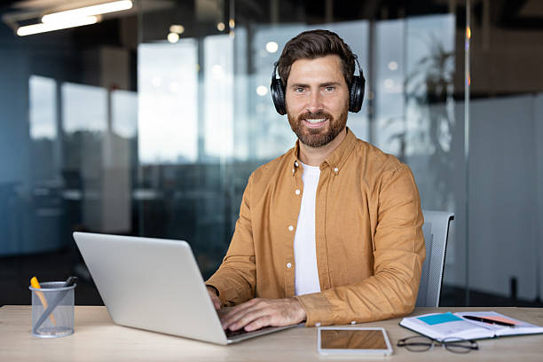 istock Professional man wearing headphones working on laptop in modern office 2241495482