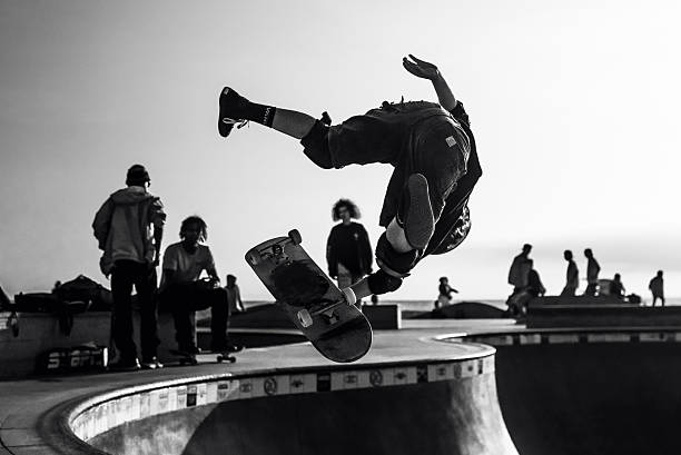 Teenagers having fun skateboarding under urban overpass with unique architectural design, girl riding on guy's skateboard while smiling