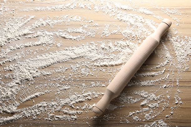 istock Scattered flour and rolling pin on wooden table, top view 2241501406