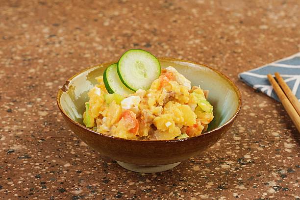 Homemade Japanese potato salad on textured brown table with soft daylight. Simple composition emphasizing traditional Asian comfort food.