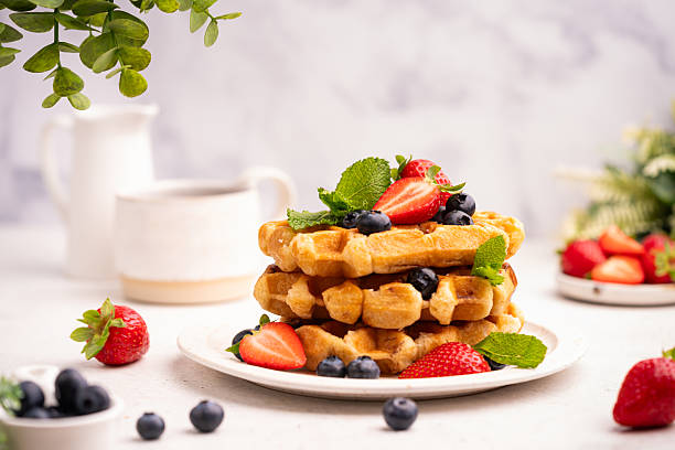Tasty Belgian waffles with fresh berries, cheese and powdered sugar on white table, close up. High quality photo