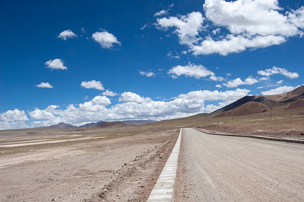istock Vast desert road under a clear blue sky with scattered clouds 2241515992