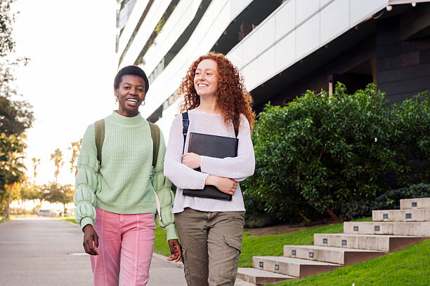 istock two young students smiling and walking down street 2241519648