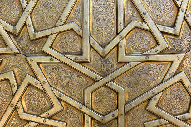 Golden-colored brass doors adorned with Moroccan patterns, metal filigree, and intricate relief work. Royal Palace, Fez, Morocco