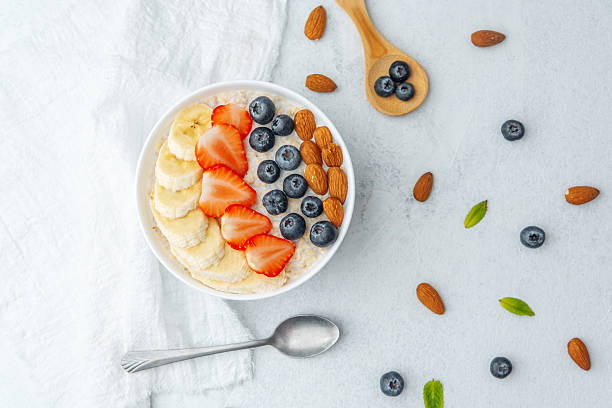 istock Oatmeal bowl with fruits and spoon and scattered nuts on table 2241520912