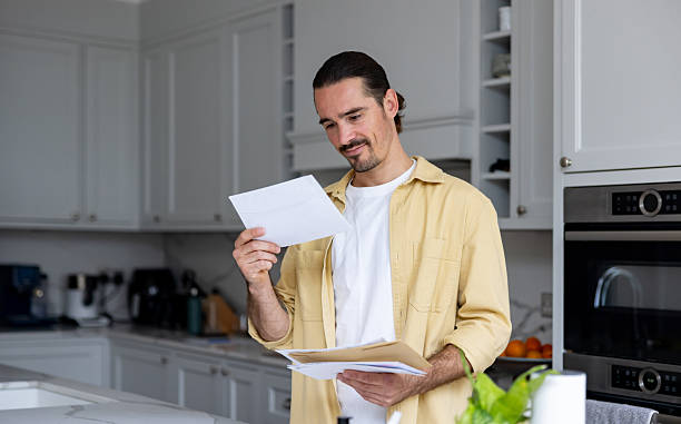 istock Man at home reading a letter in the mail 2241521427