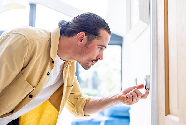 istock Man at home adjusting the temperature on the thermostat 2241521482