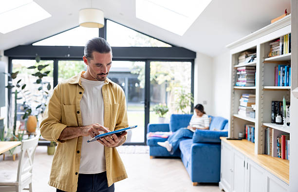 istock Man at home using a digital tablet with his wife at the background 2241521484