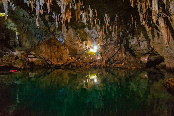A stunning view of the underground pool inside Hinagdanan Cave in Bohol, Philippines, showcasing limestone formations, stalactites, and serene turquoise waters illuminated by natural light.
