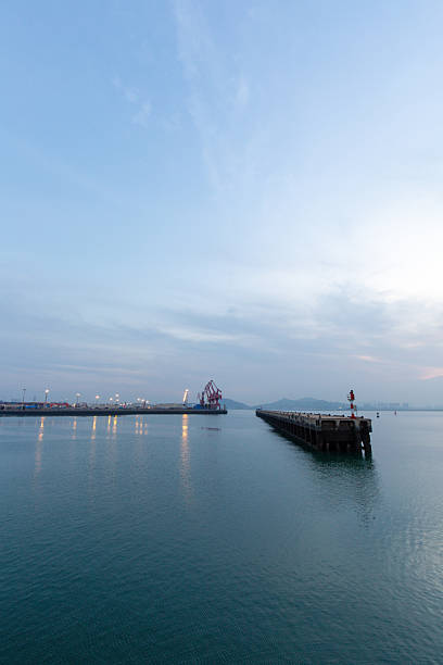 istock Serene Port Scene at Sunset with Calm Waters and Distant Cranes 2241525415