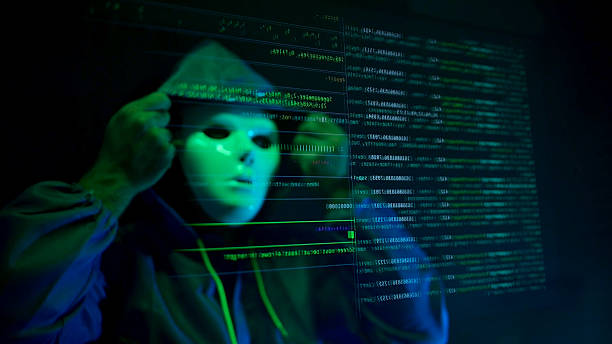 istock Anonymous hacker wearing a mask and hoodie interacting with digital data in a dark room 2241533178