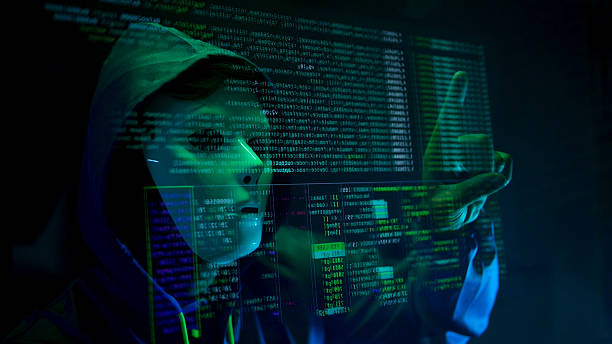 istock Anonymous hacker wearing a mask and hoodie interacting with digital data in a dark room 2241533233